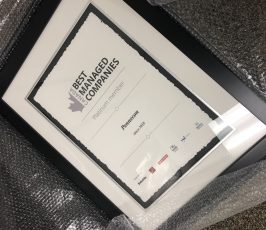 A framed certificate wrapped in bubble wrap, labeled "Canada’s Best Managed Companies," awarded to "Fincoom" as a Platinum member since 2016. Various sponsor logos appear at the bottom.