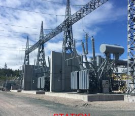 A power station with large transformers, high voltage power lines, and metal structures under a partly cloudy sky. The words "STATION TRANSFORMERS" appear in bold red text at the bottom of the image.