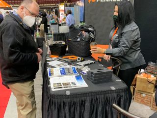 A man wearing a mask stands at a booth labeled 