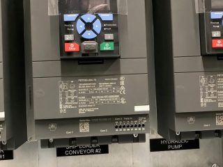 Close-up of an ABB industrial control panel with labeled buttons and a display screen, installed above a metal plate labeled 